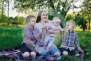 Happy family having picnic in nature. Mother with three children. Parenthood motherhood concept