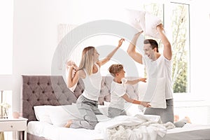 Happy family having pillow fight on bed