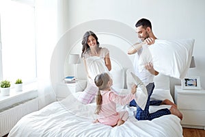 Happy family having pillow fight in bed at home