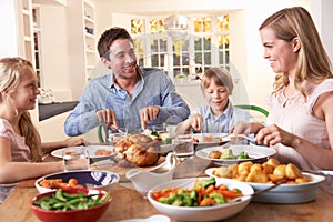 Happy family having roast chicken dinner at table photo