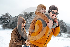 Happy family having a walk in winter outdoors in snow