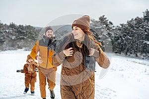 Happy family having a walk in winter outdoors in snow