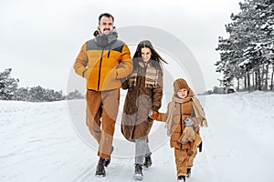 Happy family having a walk in winter outdoors in snow