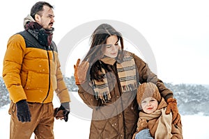 Happy family having a walk in winter outdoors in snow