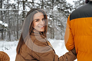 Happy family having a walk in winter outdoors in snow forest