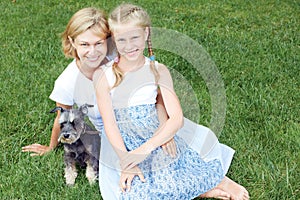 Happy family with his dog sitting on green grass and read e-book. Horizontal photo