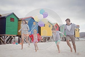 Happy family holding balloons while running at beach