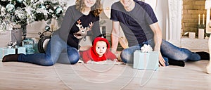 Happy family holding Christmas gifts near Xmas tree. Baby, mother and father having fun at home