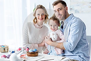 Happy family holding Easter rabbit with Easter eggs