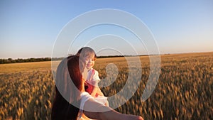 Happy family holding hands runs in field of wheat. Slow motion. Mother and daughter laughing travel holding hands with