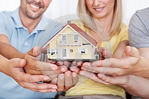 Happy family holding a model house