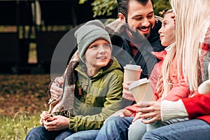 happy family holding paper cups and smiling each other