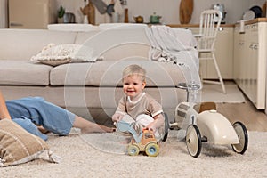 Happy family at home. Baby boy playing with toys at home indoors. Little toddler child and mother having fun together