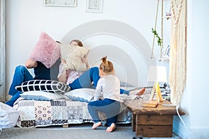 Happy family at home on the bed with pillows. Father`s Day and Mother`s Day. Mom, dad and daughter in a rustic style bedroom.