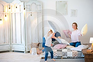 Happy family at home on the bed with pillows. Father`s Day and Mother`s Day. Mom, dad and daughter in a rustic style bedroom.