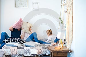 Happy family at home on the bed with pillows. Father`s Day and Mother`s Day. Mom, dad and daughter in a rustic style bedroom.