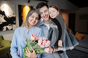 Happy family at home.Happy mother\'s day! Father and child daughter congratulate mother on holiday and give flowers