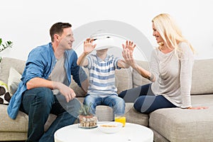Happy family at home on living room sofa having fun playing games using virtual reality headset