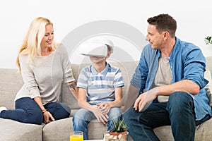 Happy family at home on living room sofa having fun playing games using virtual reality headset