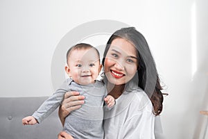 Happy family at home. Mother holding baby daughter in living room in cozy weekend morning