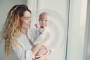 Happy family at home. Mother holding baby son in bedroom in cozy weekend