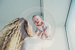 Happy family at home. Mother holding baby son in bedroom in cozy weekend