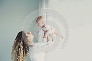 Happy family at home. Mother holding baby son in bedroom in cozy weekend