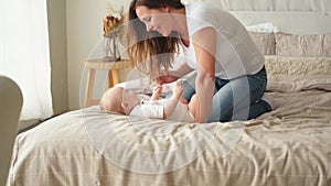 Happy family at home. Mother playing with little toddler child on bed. Mom baby relax playing having fun together