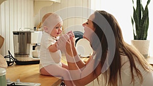 Happy family at home. Mother playing with little toddler child in kitchen. Mom baby relax playing having fun together