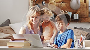 Happy family at home, mother with son and daughter have fun using computer, smiling parent with children surfing internet on