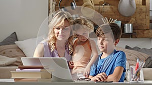 Happy family at home, mother with son and daughter have fun using computer, smiling parent with children surfing internet on