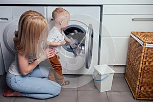 Happy family home weekend morning bathroom washing machine.mother and little son in laundry room Washer washed clothes