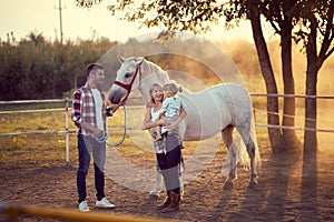 Happy family on the horse ranch .Young happy family having fun at countryside outdoors. Sunset. golden hour