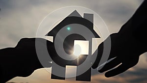 Happy family house construction concept. man holding home a paper house in his hands at lifestyle sunset silhouette