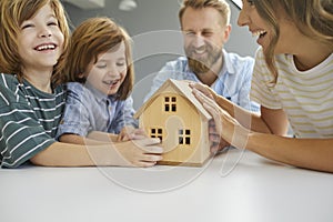 Happy family with house model illustrating concept of getting mortgage or buying new home