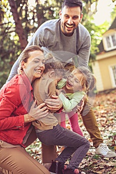 Happy family hugging itch other, autumn season in backyard.