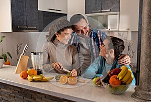Happy family, husband and wife preparing fruits for son in kitchen