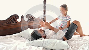 Happy Family Idyll Little Child Daughter Jump On Father Arms And They Fall On A Bed