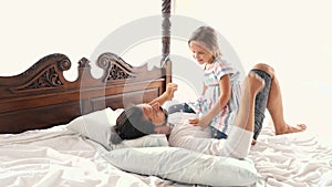 Happy Family Idyll Little Child Daughter Jump On Father Arms And They Fall On A Bed