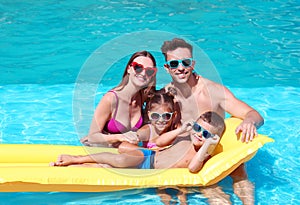 Happy family with inflatable mattress in pool