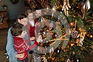 Happy family involved in decorating Christmas tree at home.