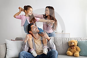 Happy family. Joyful mother, father and their daughter playing and smiling, little girl sitting on dad& x27;s shoulders
