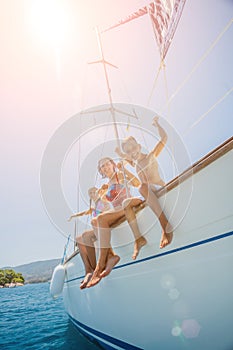 Happy family jump in sea of sailing yacht on summer cruise. Travel adventure, yachting with child on family vacation.