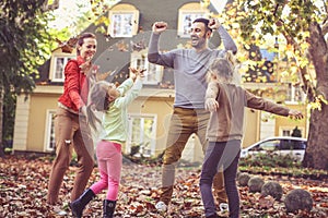 Happy family jumping at backyard. Fall leaves is fun.