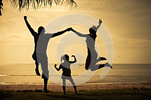 Happy family jumping on the beach on the dawn time