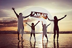 Happy family jumping on the beach at the sunset time.