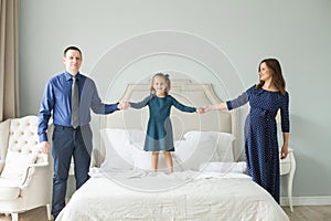 Happy family jumping on the bed. Mother, father, child daughter