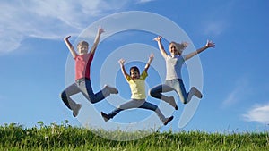 Happy family jumping on green grass hill against blue sky