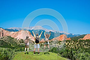 Happy family jumping with raised hands on vacation hiking trip.