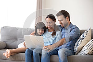 Happy family with kid daughter enjoy using laptop at home